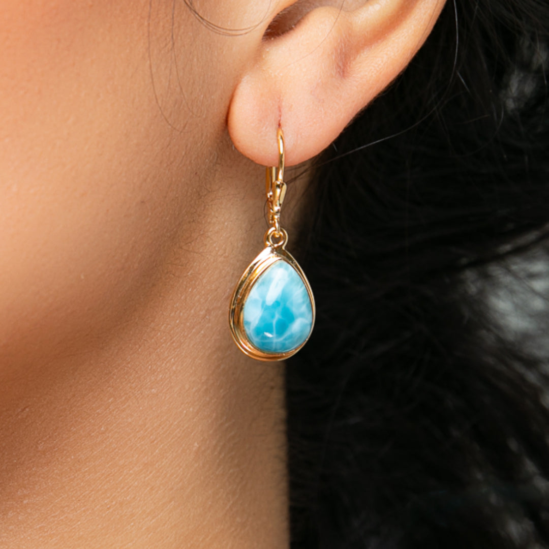 Close-up of a woman wearing Larimar gold vermeil teardrop dangle earrings featuring vibrant blue Larimar stones, showcasing their elegant and fluid design.