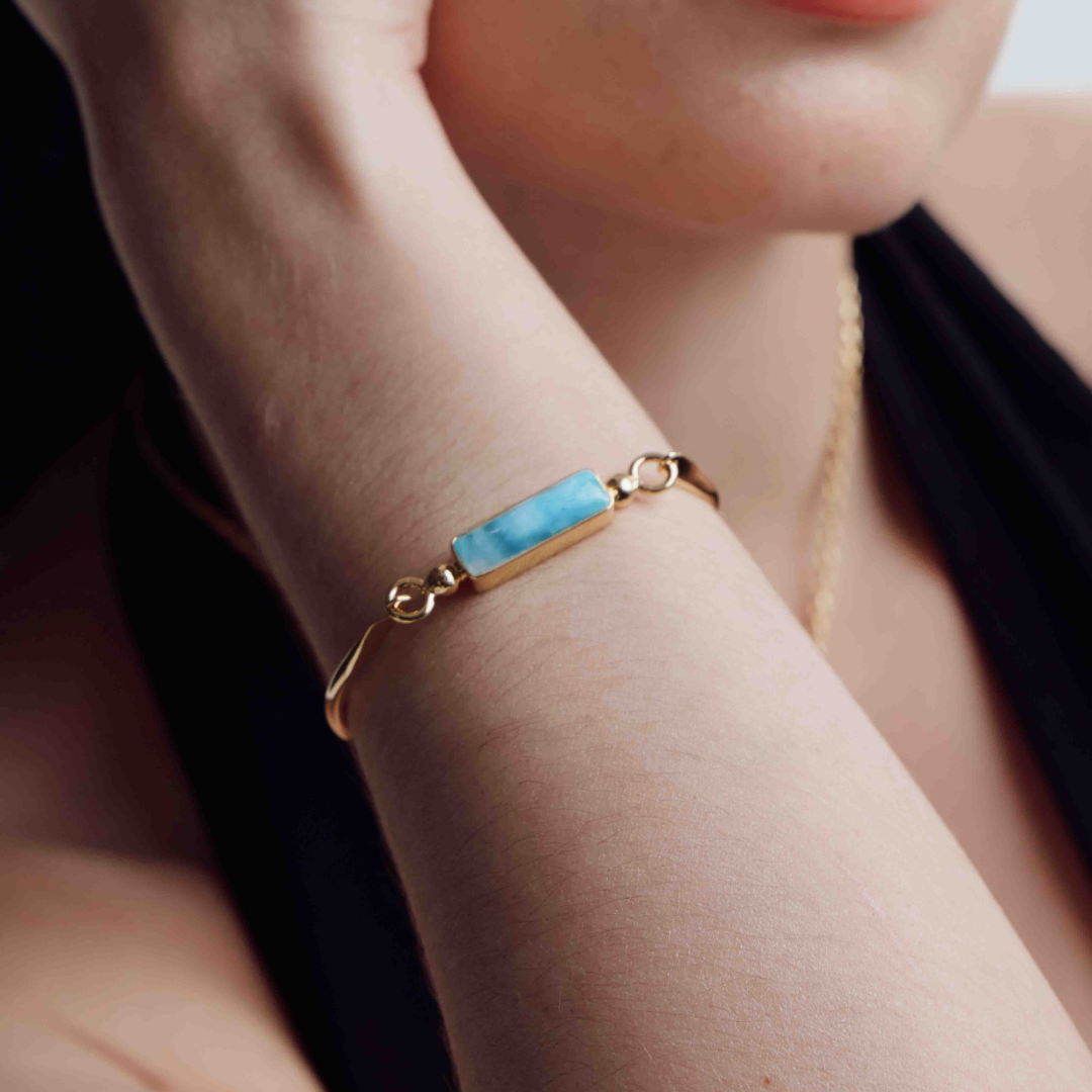 Close-up of a woman wearing stacked Larimar bangles, featuring vibrant blue gemstones set in sleek silver and gold vermeil for a stylish and sophisticated look