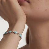 Close-up of a person wearing a bracelet with Larimar stones on a neutral background