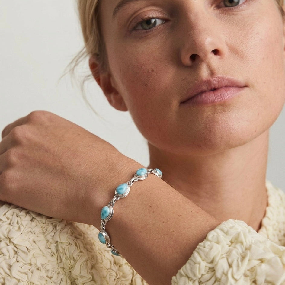 Woman wearing a Larimar bracelet with dominican blue stones on a neutral background