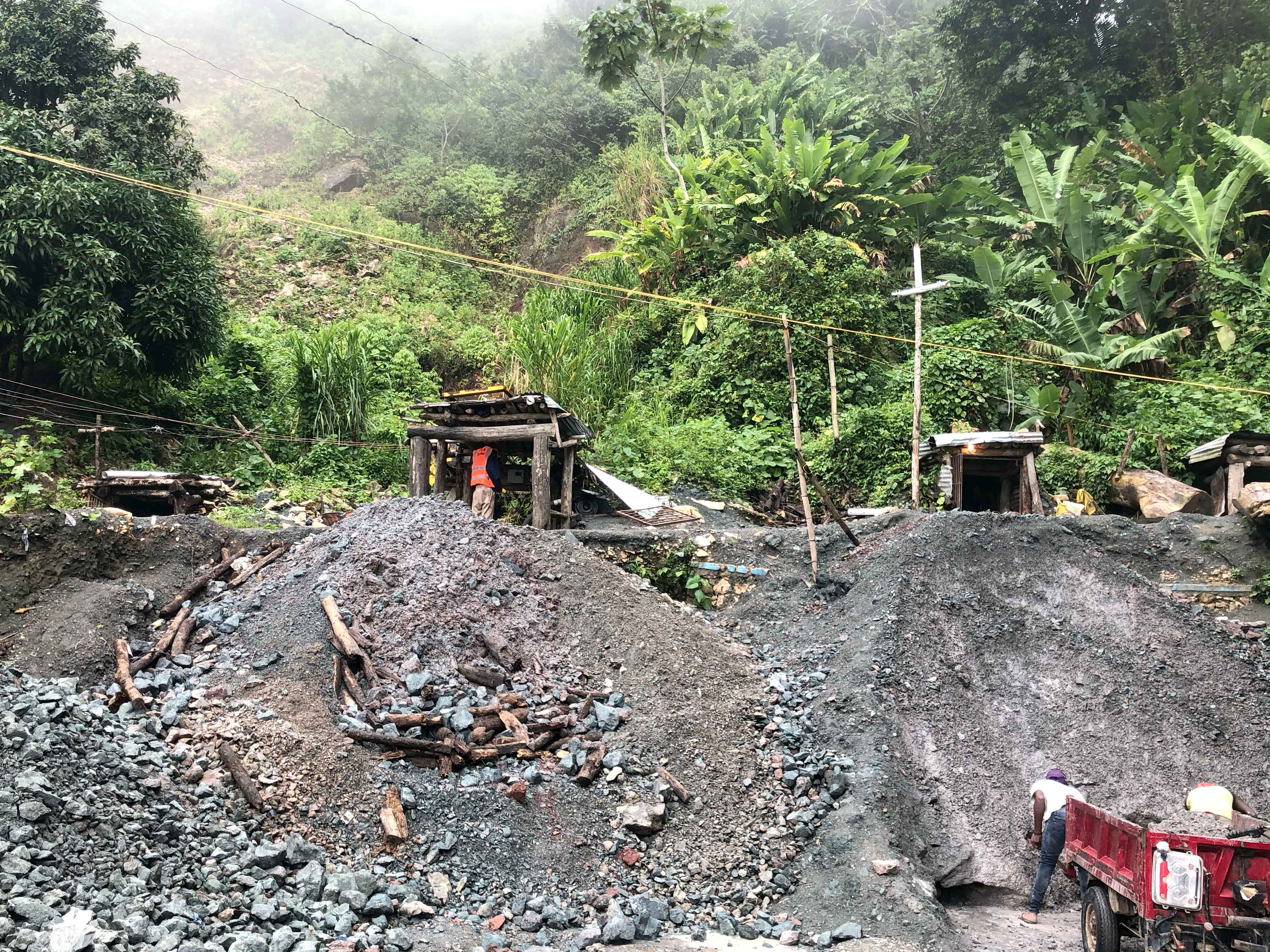 Larimar mining operation in a forested area with large piles of earth and Larimar rough rocks.