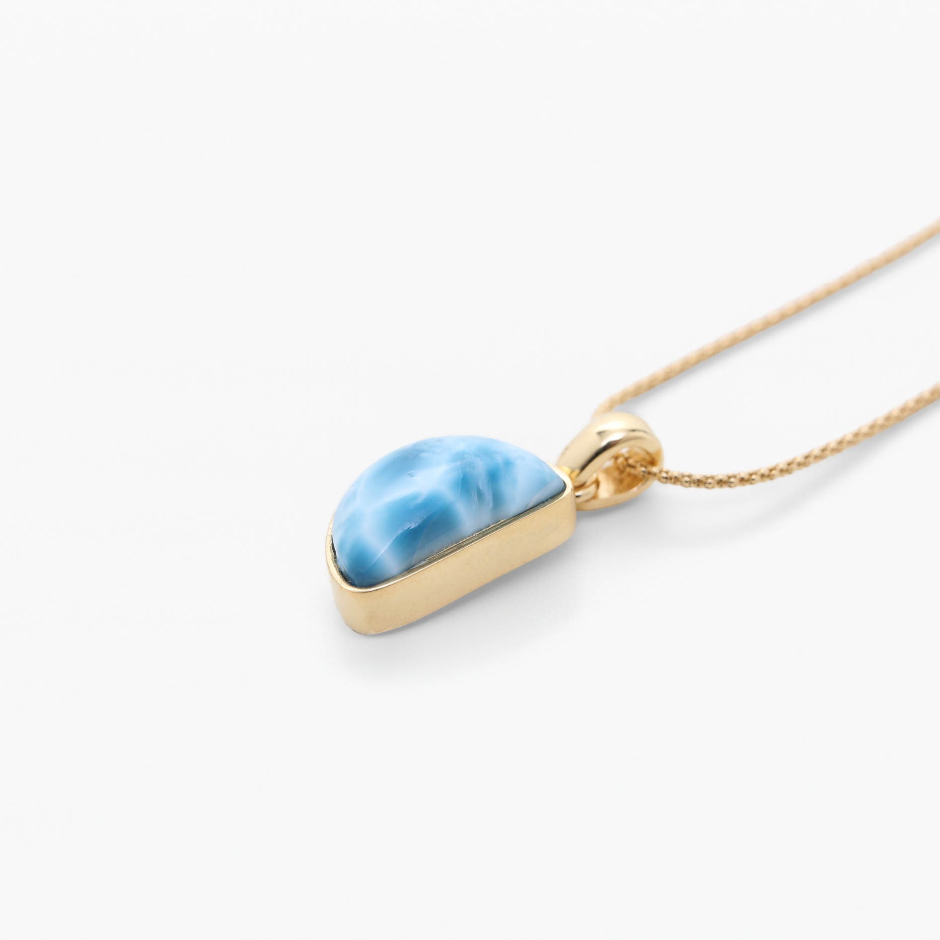 Gold necklace with a blue Larimar stone on a white background