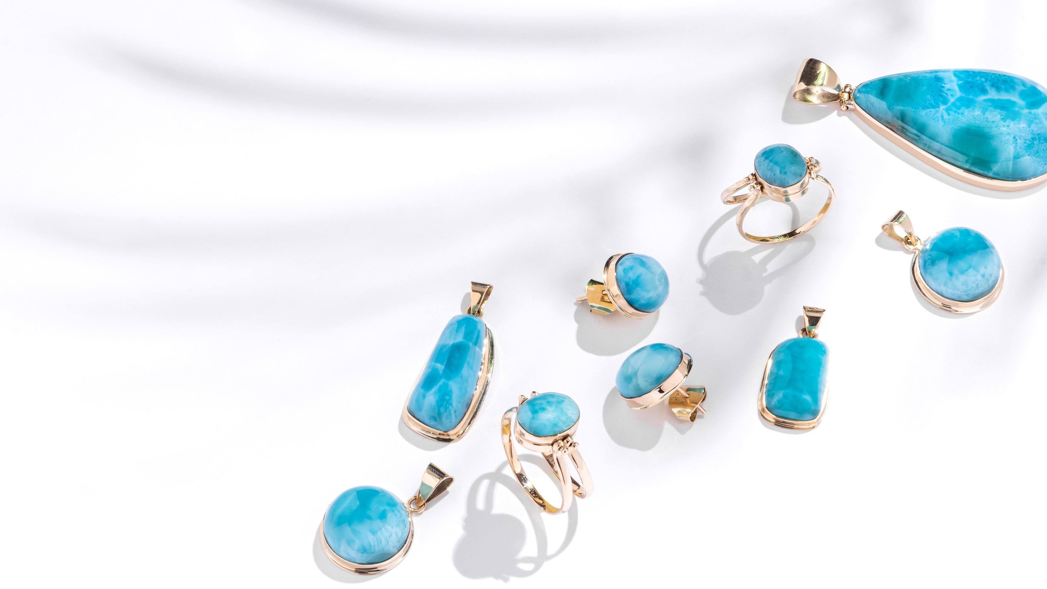 Gold jewelry set with Larimar stones on a white background