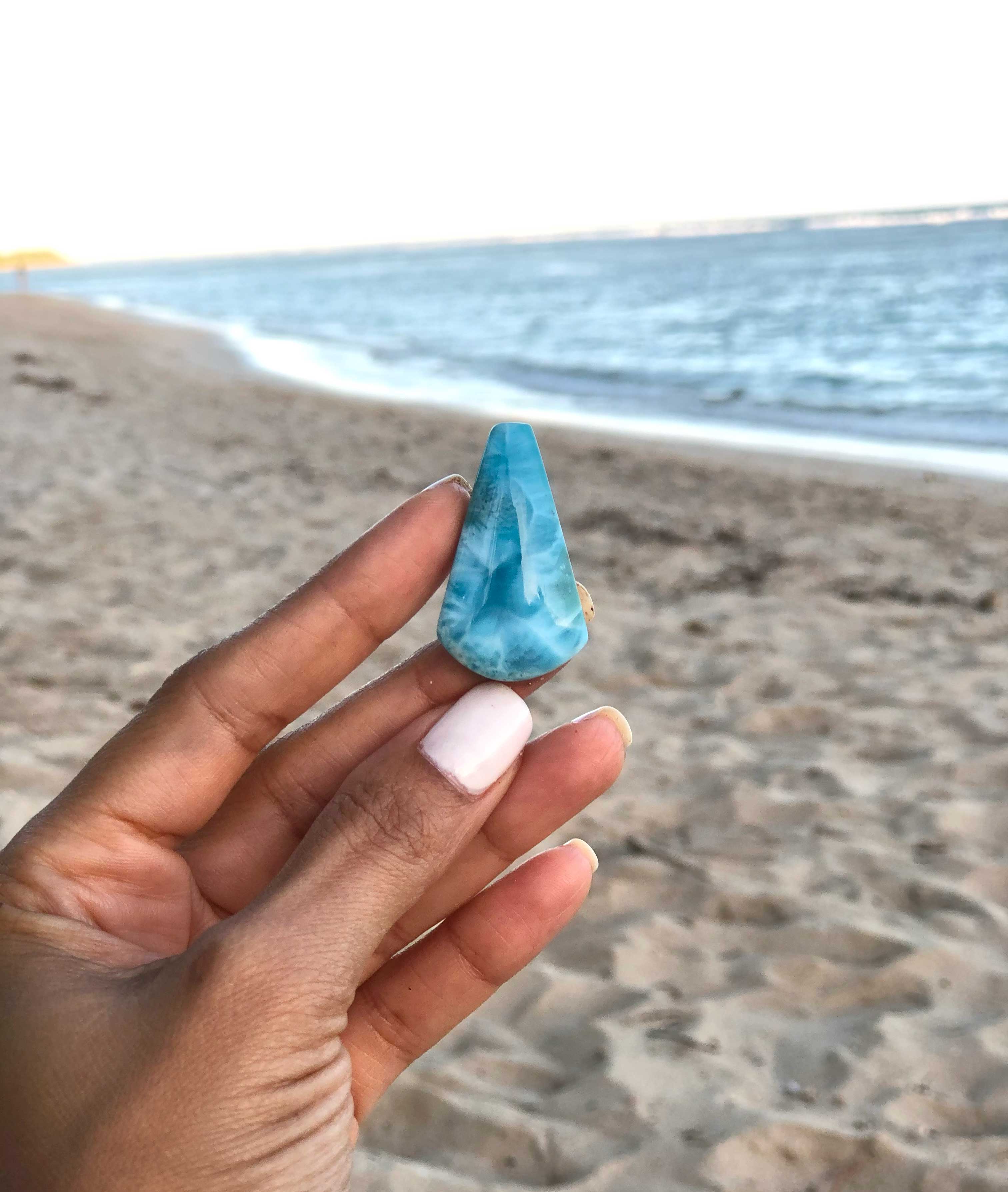Larimar gemstone held in hand on a Dominican Republic beach.