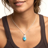 Woman wearing a necklace with a blue Larimar pendant and silver chain.