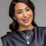 Woman wearing a Larimar Pendant Onyx  against a gray background