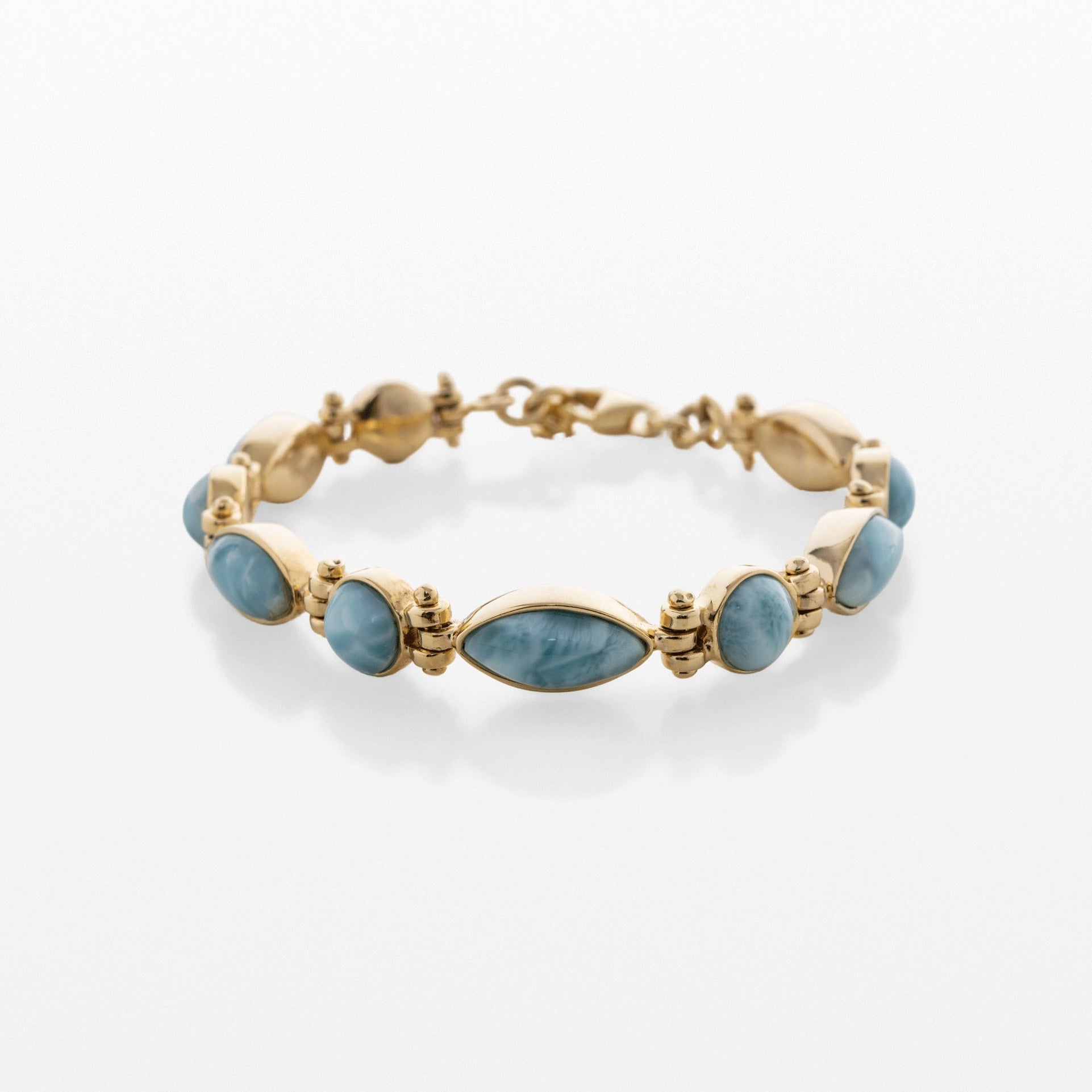 A gold bracelet featuring a row of oval-shaped Larimar blue stones, displayed on a clean white background with a soft reflection.