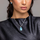 Woman wearing a black sleeveless top and Teardrop Larimar Pendant with a gray background
