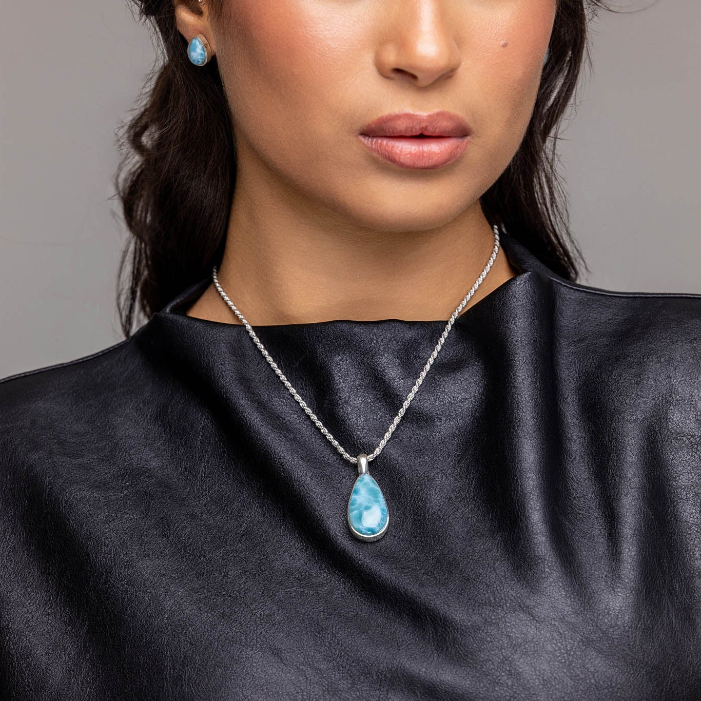 Woman wearing a black sleeveless top and Teardrop Larimar Pendant with a gray background