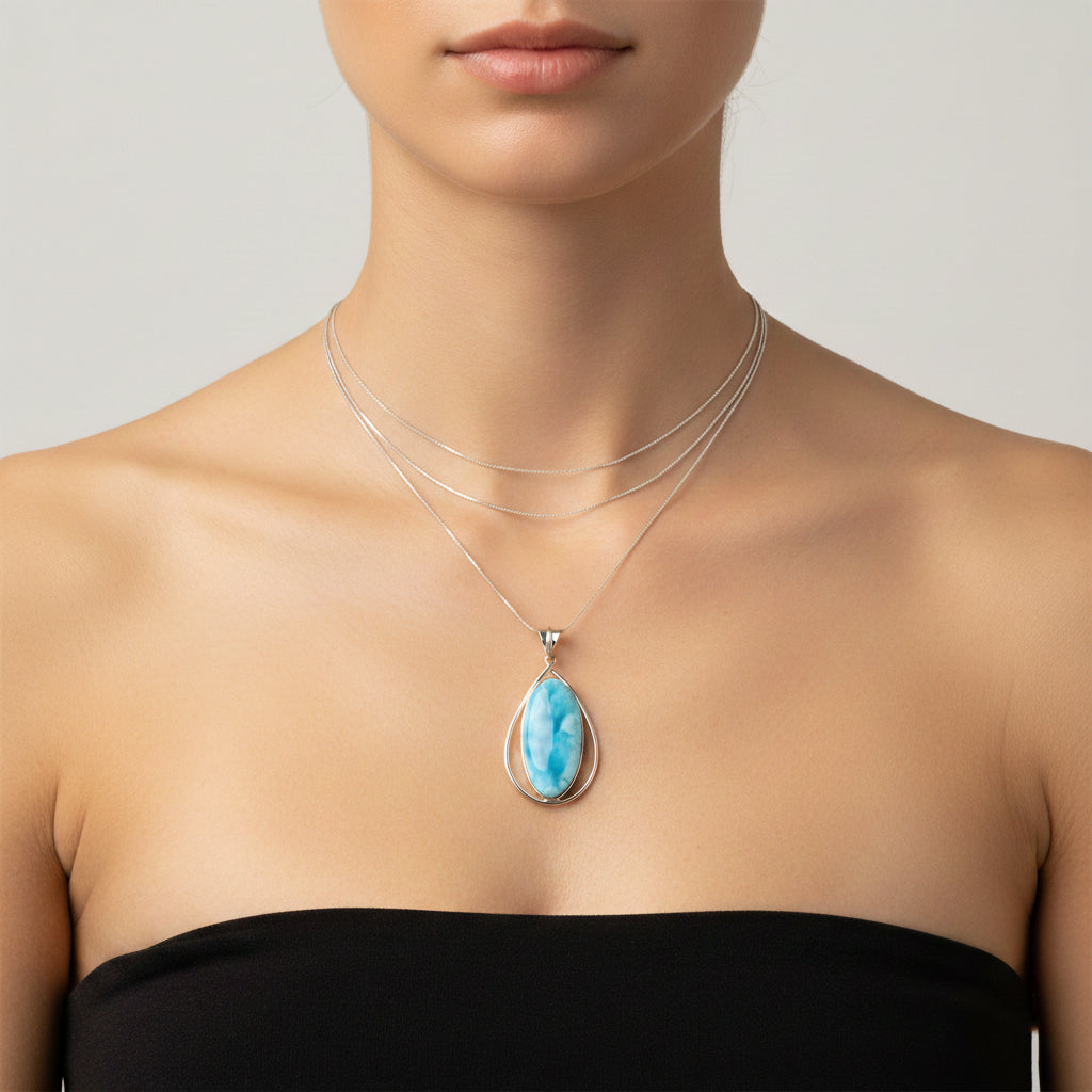 Necklace with a blue Larimar pendant worn by a person on a neutral background