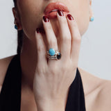 Woman wearing a reversible ring with a blue Larimar gemstone against a neutral background