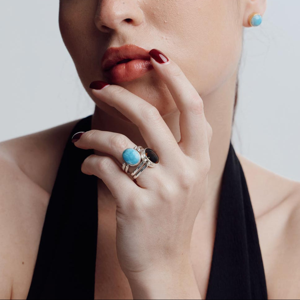 Woman wearing a reversible ring with a blue Larimar gemstone against a neutral background