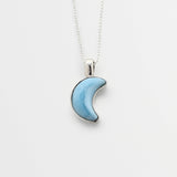 Blue Larimar crescent moon pendant on a silver chain against a white background